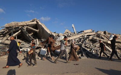 People, some carrying aid parcels, walk along the Salah al-Din road near the Nuseirat refugee camp, in the central Gaza Strip, used by food-seeking Palestinians to reach an aid distribution point set up by the privately-run, US- and Israeli-backed Gaza Humanitarian Foundation (GHF), on June 25, 2025. (Photo by Eyad BABA / AFP)