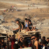 Children transporting wooden pallets ride along the Salah al-Din road near the Nuseirat refugee camp in the central Gaza Strip, used by food-seeking Palestinians to reach an aid distribution point set up by the Gaza Humanitarian Foundation (GHF), June 25, 2025. (Eyad Baba / AFP)
