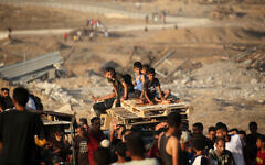 Illustrative: Children transporting wooden pallets ride along the Salah al-Din road near the Nuseirat refugee camp in the central Gaza Strip, used by food-seeking Palestinians to reach an aid distribution point set up by the Gaza Humanitarian Foundation (GHF), June 25, 2025. (Eyad BABA / AFP)