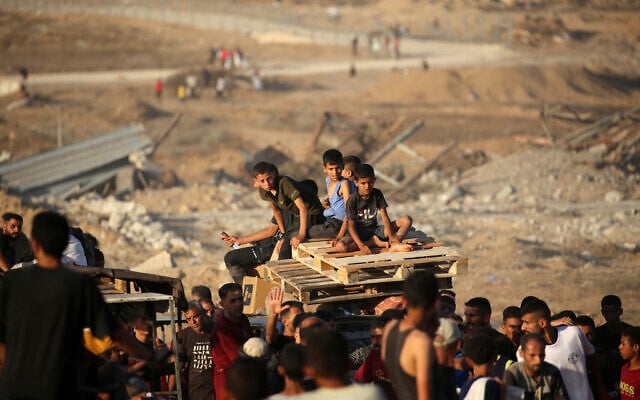 Children transporting wooden pallets ride along the Salah al-Din road near the Nuseirat refugee camp in the central Gaza Strip, used by food-seeking Palestinians to reach an aid distribution point set up by the Gaza Humanitarian Foundation (GHF), June 25, 2025. (Eyad Baba / AFP)