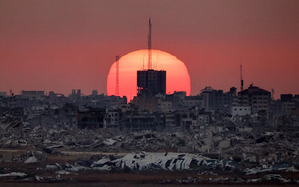 This picture taken from Israel shows the sun setting behind destroyed buildings in Gaza, on July 1, 2025. (Jack GUEZ / AFP)