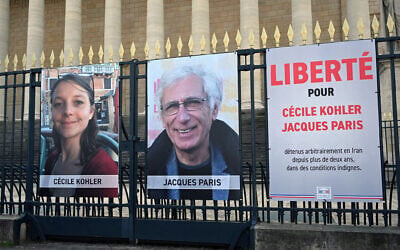 Portraits of French national Cecile Kohler (L) currently imprisoned in Iran with her partner French national Jacques Paris (C) along with a placard reading "Freedom for Cecile Kohler and Jacques Paris arbitrarily detained in Iran for over two years in appalling conditions" outside the Palais Bourbon, France's National Assembly, in Paris, on March 25, 2025. (Bertrand GUAY / AFP)