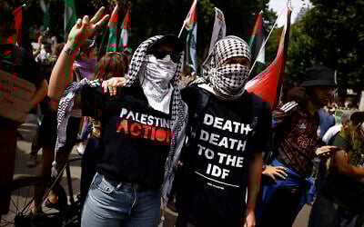 Anti-Israel protesters, one wearing a shirt reading 'death, death to the IDF,' gather outside the High Court in London on July 4, 2025. (BENJAMIN CREMEL / AFP)