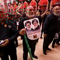A devotee holds portraits of Iran's supreme leader Ayatollah Ali Khamenei (R) and the late supreme leader Ayatollah Ruhollah Khomeini in the Iraqi holy city of Karbala, on July 6, 2025. (AHMAD AL-RUBAYE / AFP)