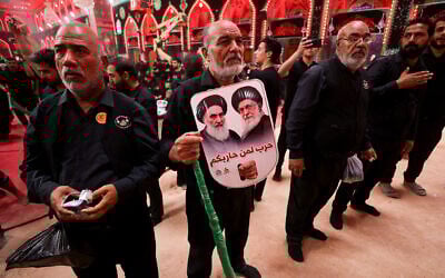 A devotee holds portraits of Iran's supreme leader Ayatollah Ali Khamenei (R) and the late supreme leader Ayatollah Ruhollah Khomeini in the Iraqi holy city of Karbala, on July 6, 2025. (AHMAD AL-RUBAYE / AFP)