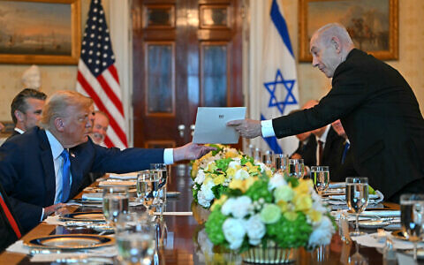 Prime Minister Benjamin Netanyahu (R) hands over a letter to US President Donald Trump as they meet at the Blue Room of the White House in Washington, DC, on July 7, 2025. (Photo by ANDREW CABALLERO-REYNOLDS / AFP)