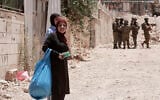 Palestinian women carry their belongings as Israeli soldiers enforce an evacuation order on a house in the Jenin refugee camp in the West Bank on July 8, 2025. (Jaafar ASHTIYEH / AFP)