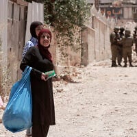 Palestinian women carry their belongings as Israeli soldiers enforce an evacuation order on a house in the Jenin refugee camp in the West Bank on July 8, 2025. (Jaafar ASHTIYEH / AFP)