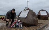 A man puts a candle by new plaques recently placed near a Polish monument to Jews murdered by their Polish neighbors in the 1941 Jedwabne massacre, July 10, 2025. (Wojtek RADWANSKI / AFP)