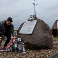A man puts a candle by new plaques recently placed near a Polish monument to Jews murdered by their Polish neighbors in the 1941 Jedwabne massacre, July 10, 2025. (Wojtek RADWANSKI / AFP)