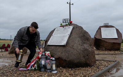 A man puts a candle by new plaques recently placed near a Polish monument to Jews murdered by their Polish neighbors in the 1941 Jedwabne massacre, July 10, 2025. (Wojtek RADWANSKI / AFP)
