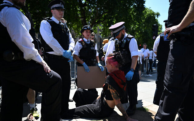 A protester alongside waits with police officers for a police van after being arrested makes a peace sign with their hand as people gather in support of the banned anti-Israel group Palestine Action, in Parliament Square, London on July 12, 2025. (JUSTIN TALLIS / AFP) A protester alongside waits with police officers for a police van after being arrested makes a peace sign with their hand as people gather in support of the banned anti-Israel group Palestine Action, in Parliament Square, London on July 12, 2025. (JUSTIN TALLIS / AFP)
