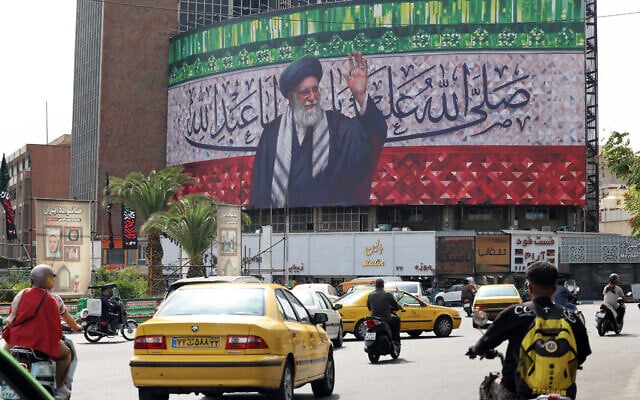 Motorists drive their vehicles past a billboard depicting Iran's Supreme Leader Ayatollah Ali Khamenei, in the center of Tehran's Valiasr Square, on July 13, 2025. (ATTA KENARE / AFP)
