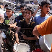 Children queue with pots to receive meals from a charity kitchen in Gaza City on July 14, 2025. (BASHAR TALEB / AFP)