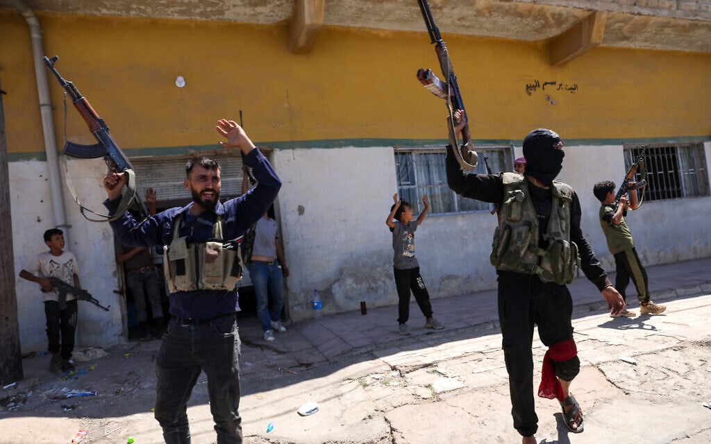 Members of Syria's security forces and children holding rifles celebrate in the predominantly Bedouin-inhabited al-Mouqawwas neighbourhood in Sweida on July 15, 2025, following clashes between Bedouin tribes and Druze fighters. (Photo by Bakr ALKASEM / AFP)