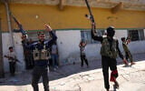 Members of Syria's security forces and children holding rifles celebrate in the predominantly Bedouin-inhabited al-Mouqawwas neighbourhood in Sweida on July 15, 2025, following clashes between Bedouin tribes and Druze fighters. (Photo by Bakr ALKASEM / AFP)