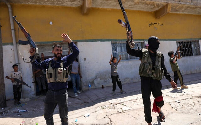 Members of Syria's security forces and children holding rifles celebrate in the predominantly Bedouin-inhabited al-Mouqawwas neighbourhood in Sweida on July 15, 2025, following clashes between Bedouin tribes and Druze fighters. (Photo by Bakr ALKASEM / AFP)