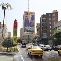 Traffic flows in Tehran past a huge billboard bearing a painting of a missile falling on Israel with the slogan in Farsi, "The missile has fallen amidst the demons," on July 16, 2025 (ATTA KENARE / AFP)