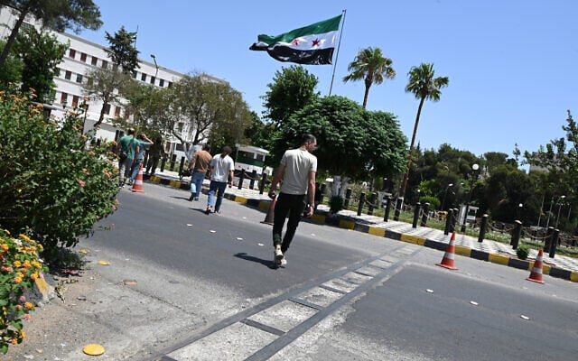 Syrians cross a road next to the Ministry of Defense near Damascus' Ummayad Square, after Israel said it hit the nearby military headquarters with a drone strike on July 16, 2025. (Photo by AFP)