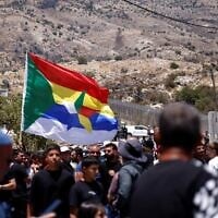 Druze wait near the border fence in the Golan Heights village of Majdal Shams, as Syrian Druze who had crossed over the day before cross back to return to Syria, on July 17, 2025. (Jalaa MAREY / AFP)