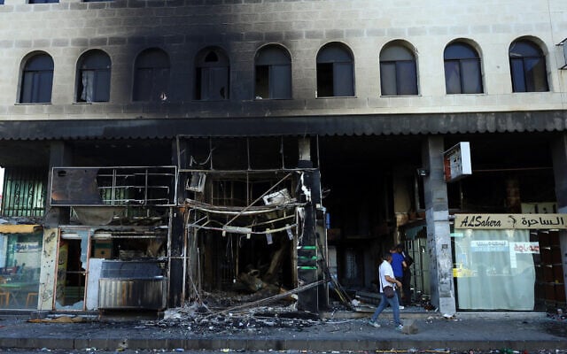 People assess the damage in a building after Syrian government forces pulled out of the southern Sweida governorate, on July 17, 2025. (Photo by Shadi AL-DUBAISI / AFP)