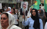 A Kurdish Syrian woman carries an image of a Druze elder Sheikh Merhej Shahin as a man in military attire forcibly shaved off his moustache, during a march in support of the people of Sweida in the eastern city of Qamishli on July 17, 2025. (Delil Souleiman/AFP)