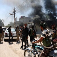 Fighters from Bedouin tribes gather near a burning building in al-Mazraa village, in Syria's southern Sweida governorate, as clashes with Druze gunmen continue on July 18, 2025 (OMAR HAJ KADOUR / AFP)