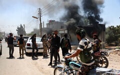 Fighters from Bedouin tribes gather near a burning building in al-Mazraa village, in Syria's southern Sweida governorate, as clashes with Druze gunmen continue on July 18, 2025 (OMAR HAJ KADOUR / AFP)