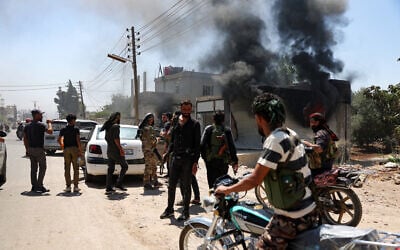 Fighters from Bedouin tribes gather near a burning building in al-Mazraa village, in Syria's southern Sweida governorate, as clashes with Druze gunmen continue on July 18, 2025 (OMAR HAJ KADOUR / AFP)