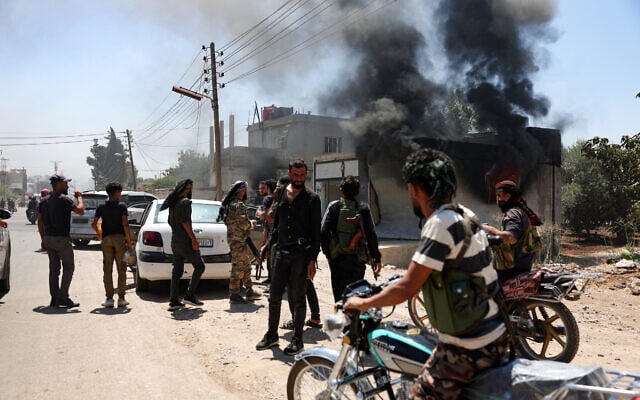 Fighters from Bedouin tribes gather near a burning building in al-Mazraa village, in Syria's southern Sweida governorate, as clashes with Druze gunmen continue on July 18, 2025 (OMAR HAJ KADOUR / AFP)