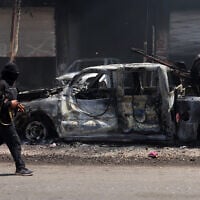 A fighters from Bedouin tribes walks past a burnt vehicle in al-Mazraa village in Syria's southern Sweida governorate, July 18, 2025. (Bakr ALKASEM / AFP)