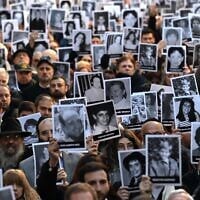 People hold pictures of victims during a ceremony to commemorate the 31st anniversary the Mutual Israelite Association of Argentina (AMIA) terror bombing, which killed 85 and wounded more than 300, in Buenos Aires on July 18, 2025. (Luis Robayo/AFP)