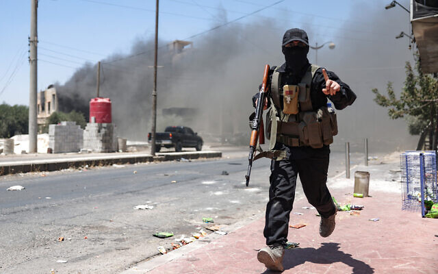 Heavy smoke rises as a member of Bedouin and tribal forces runs during clashes with Druze fighters in Syria's southern city of Sweida on July 19, 2025. (OMAR HAJ KADOUR / AFP) Heavy smoke rises as a member of Bedouin and tribal forces runs during clashes with Druze fighters in Syria's southern city of Sweida on July 19, 2025. (OMAR HAJ KADOUR / AFP)