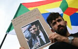 A protestor holds a sign reading "The new 'President' of Syria was, is and will stay a terrorist" in front of a Druze flag bearing the Druze star during a demonstration in support of the Syrian Druze community at Place du Trocadero, in Paris on July 19, 2025. (Bertrand GUAY / AFP)