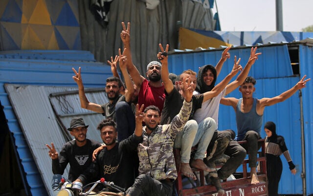 Men gesture as they ride ride together in the back of a tricycle cart along Salaheddin road in Deir el-Balah in the central Gaza Strip on July 21, 2025. (Photo by Eyad BABA / AFP)