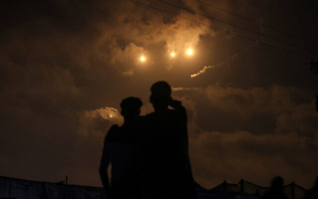 Displaced Palestinians watch from the al-Mawasi refugee camp as flares launched by Israeli forces light up the sky above nearby Khan Younis in the southern Gaza Strip on July 21, 2025. (AFP)