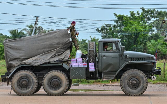A Cambodian soldier stands on a truck carrying a Russian-made BM-21 rocket launcher travelling along a street in Oddar Meanchey province on July 26, 2025. (TANG CHHIN Sothy / AFP)