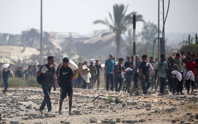 Displaced Palestinians at the Nuseirat refugee camp haul food parcels and other items they managed to get from a GHF aid distribution point at the Netzarim corridor in the central Gaza Strip. on July 26, 2025. (Eyad BABA / AFP)