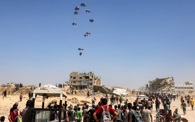 Illustrative: People gather as a C-130 Hercules military transport aircraft drops humanitarian aid on the northern Gaza Strip on July 27, 2025. (Bashar Taleb/AFP)