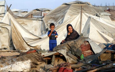 A woman and a boy sit by debris and destroyed tents following overnight Israeli bombardment at a camp sheltering in displaced in the northwest of Khan Yunis in the southern Gaza Strip on July 28, 2025. (AFP)