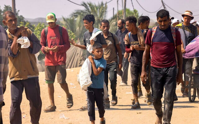 Palestinians carry personal belongings as they walk in the Mawasi area of Rafah in the southern Gaza Strip on July 28, 2025. (AFP)