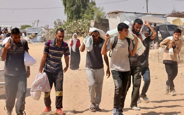 Palestinians carry humanitarian aid they received at the Rafah corridor as they walk in the Mawasi area of Rafah in the southern Gaza Strip on July 30, 2025. (Photo by AFP)