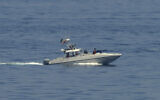 An Iranian Revolutionary Guard vessel watches an American warship in the Strait of Hormuz May 19, 2023. (Jon Gambrell/AP)