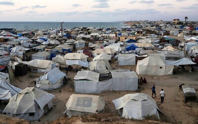 Palestinians displaced by the Israeli air and ground offensive on the Gaza Strip, stand in an area at a makeshift tent camp at dusk in Khan Younis, southern Gaza, July 2, 2025. (AP Photo/Abdel Kareem Hana)