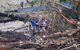 People climb over debris on a bridge atop the Guadalupe River after a flash flood swept through the area, July 5, 2025, in Ingram, Texas. (AP Photo/Julio Cortez)