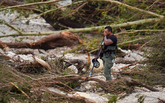 A sheriff's deputy pauses while combing through the banks of the Guadalupe River near Camp Mystic after a flash flood swept through the area, in Hunt, Texas, July 5, 2025. (Julio Cortez/AP)