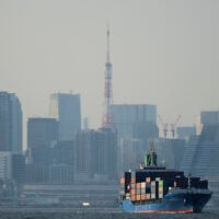 Tokyo Tower is seen amid tall buildings as a container ship leaves a cargo terminal in Tokyo, April 9, 2025. (AP Photo/Hiro Komae, File)