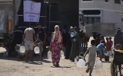 Palestinians carry containers for water at a camp for the displaced in Deir al-Balah, Gaza Strip, July 7, 2025. (AP Photo/Abdel Kareem Hana)