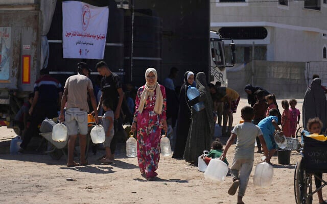 Palestinians carry containers for water at a camp for the displaced in Deir al-Balah, Gaza Strip, July 7, 2025. (AP Photo/Abdel Kareem Hana)