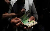 A Palestinian vegetable merchant shows worn-out Israeli currency, July 9, 2025, in Gaza City. (AP/Jehad Alshrafi)